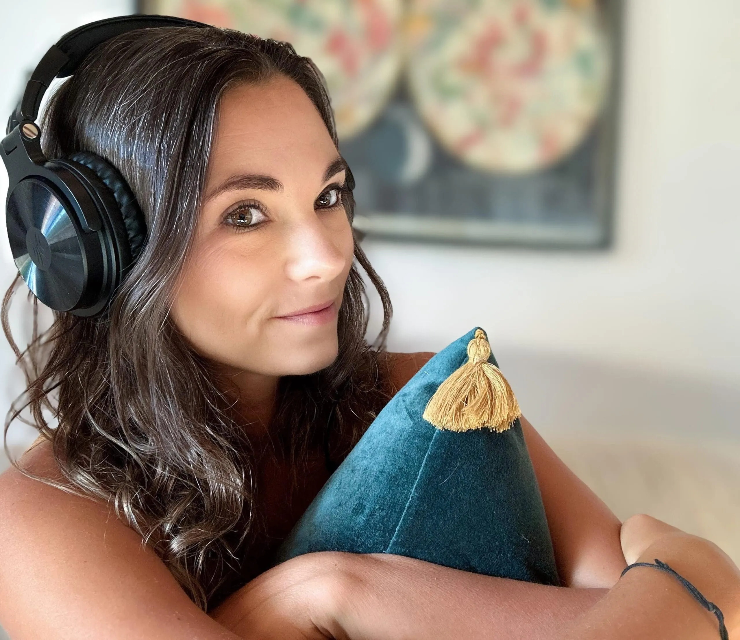 Emma Clark wearing headphones, listening to SSP, holding a green pillow, looking pensive but happy